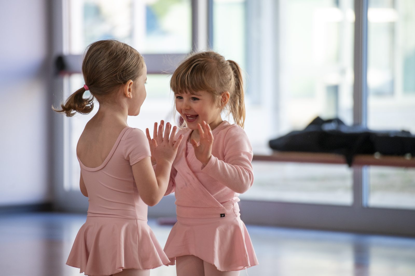 Due bambine in body rosa giocano insieme durante una lezione di Gioco Danza