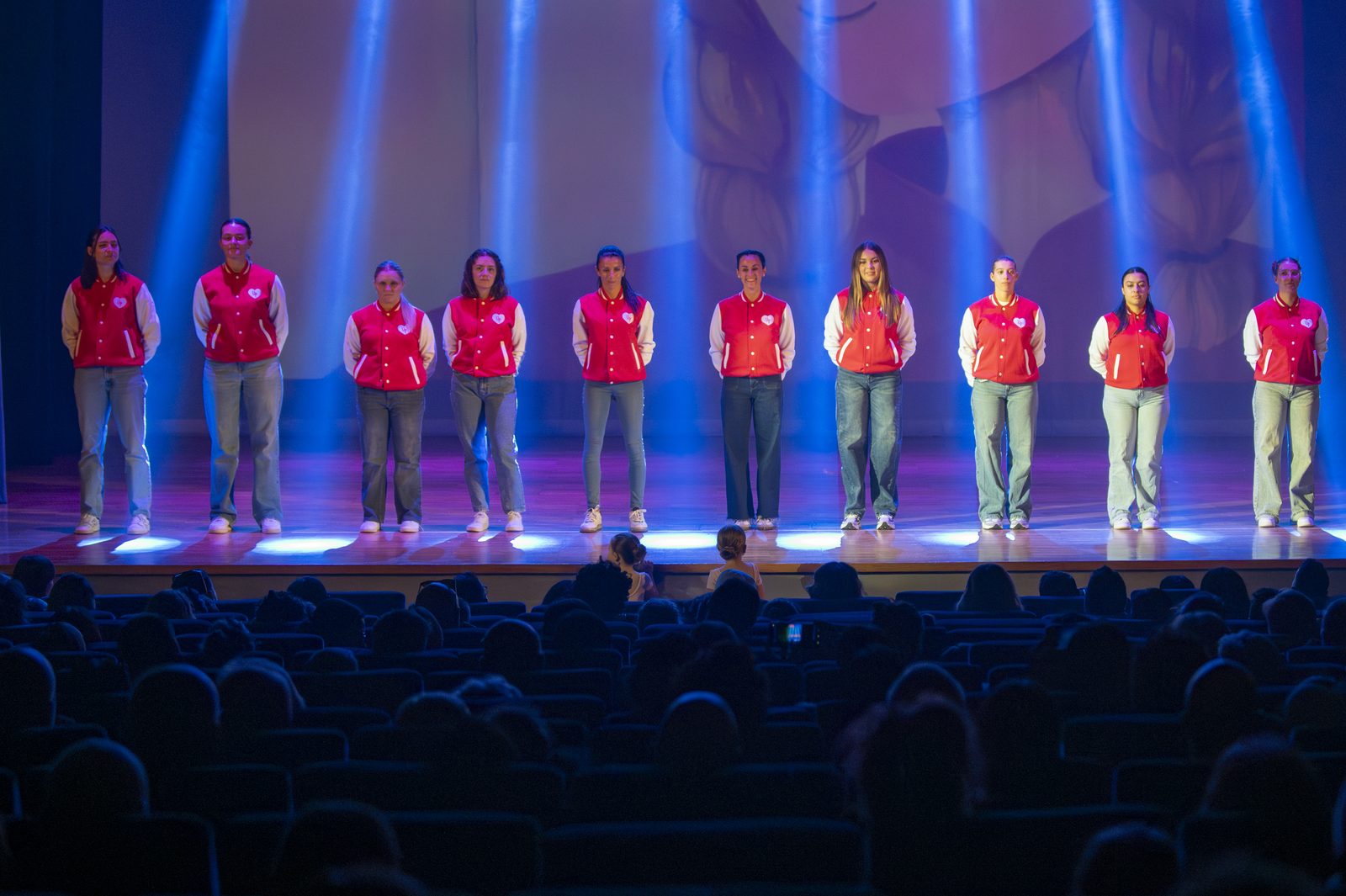 Le insegnanti di Up A.s.d. con la giacca rossa schierate sul palco del teatro